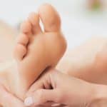 Image of the hands of a practitioner giving a foot reflexology massage.
